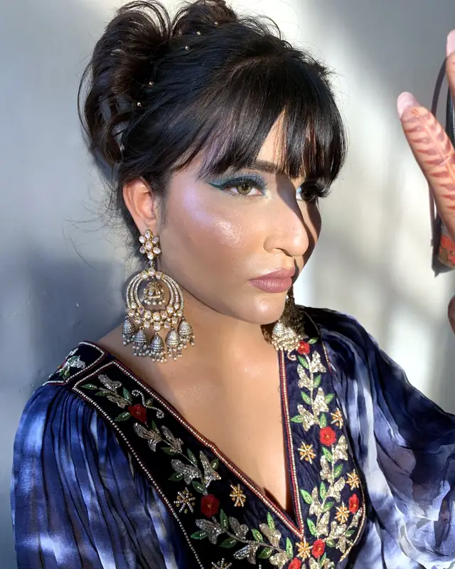 Fashion makeup look with teal winged eyeliner, worn with a navy tie-dye embroidered jacket, not bridal